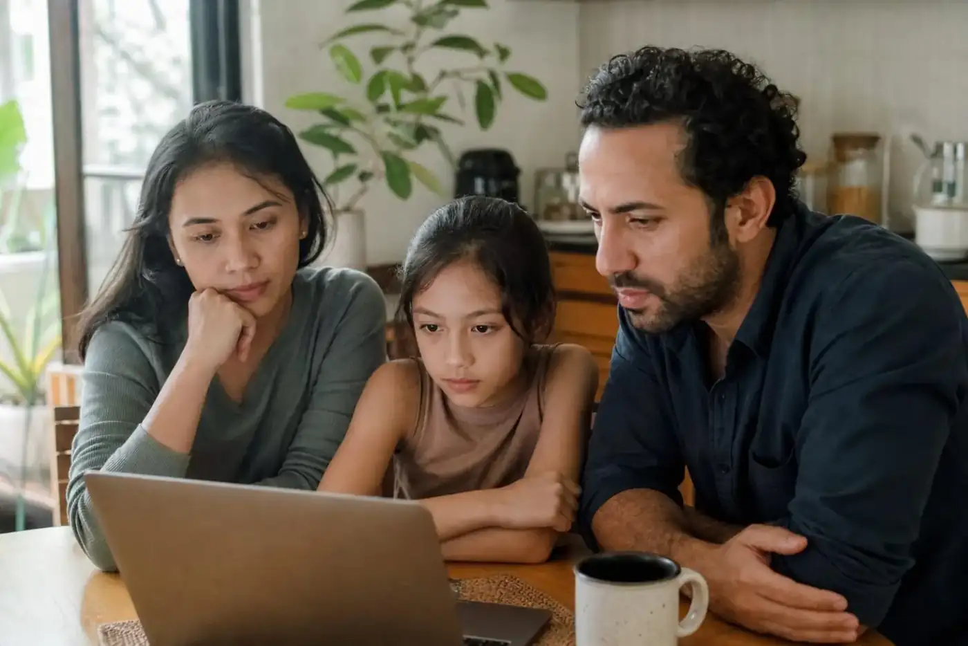 A globally mixed family at home together considering international school options on a laptop